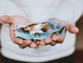 Man with his hands out holding a fist-full of money