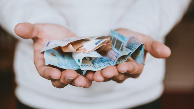 christian-dubovan-686398-unsplash_15-07-2018 Man with his hands out holding a fist-full of money